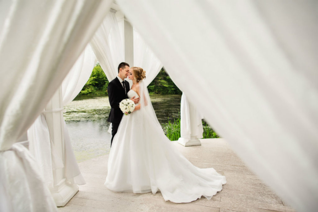 Bride and groom embracing under white drapery