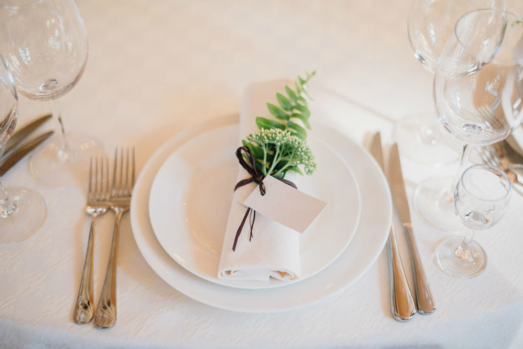 Elegant table setting with tied napkin and greenery