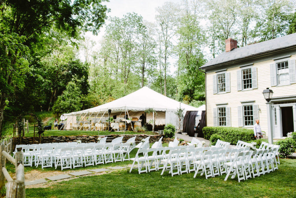 Outdoor wedding ceremony with tent and white chairs
