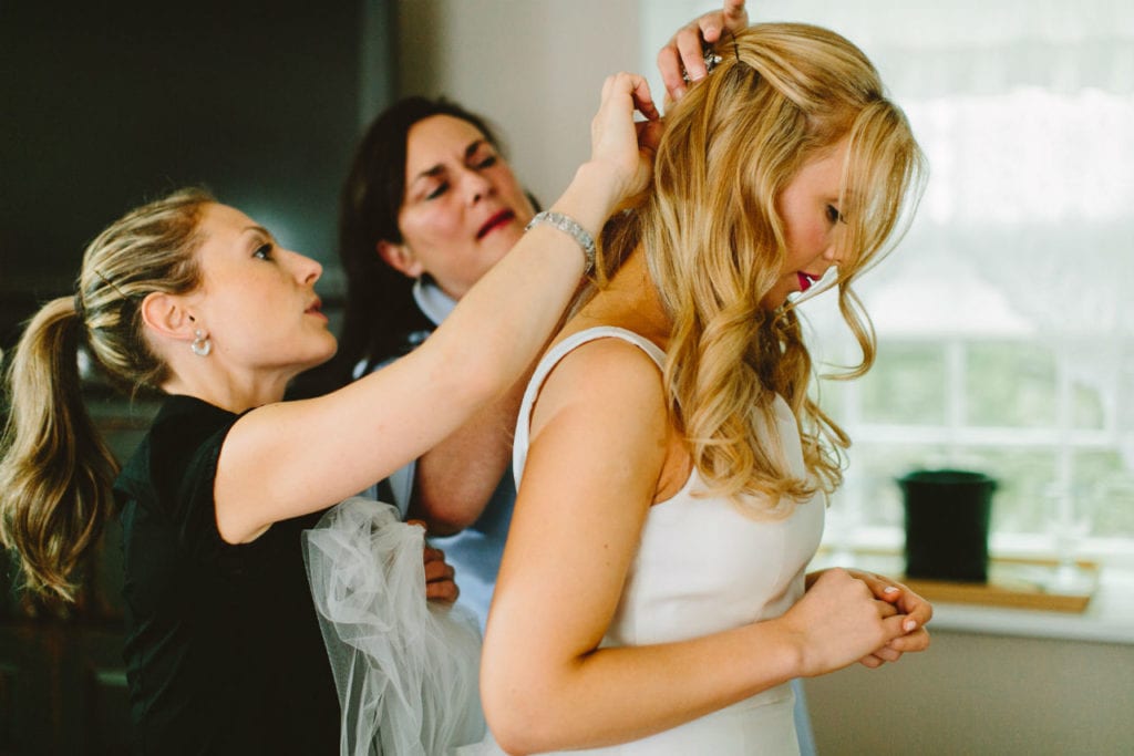 Bridesmaids fastening veil on bride